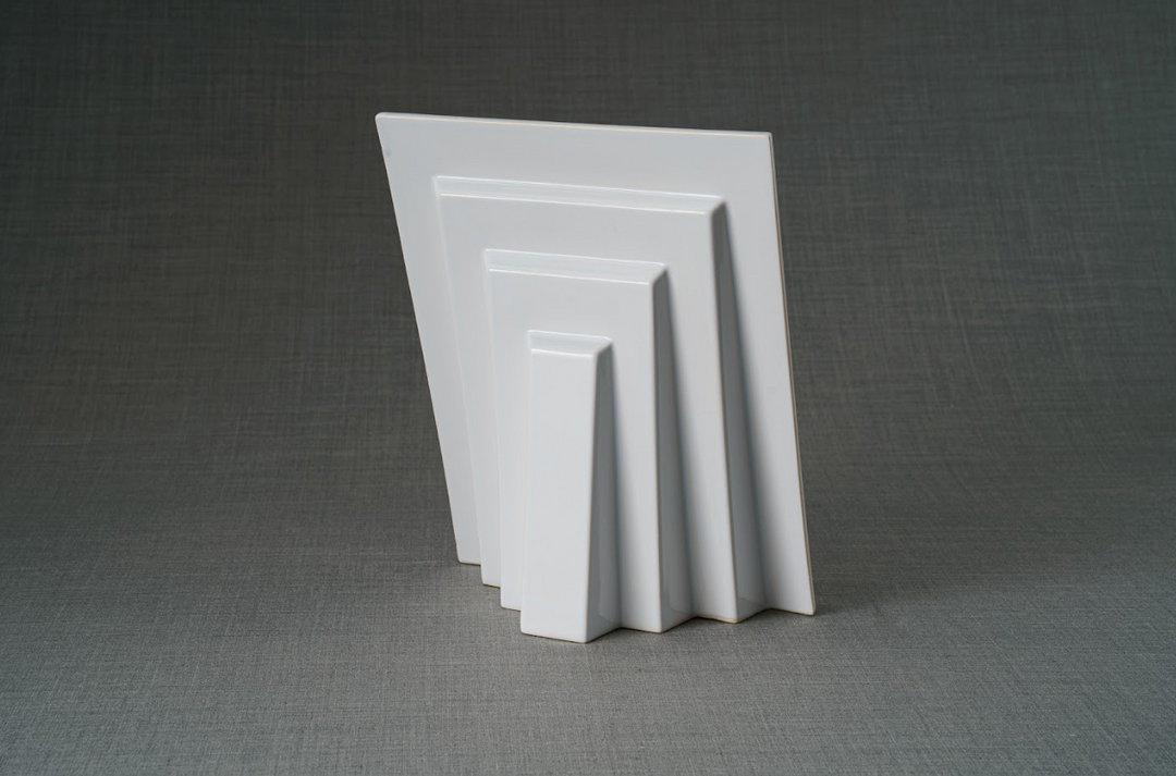 White nested ceramic frames in a stepped display against a gray background
