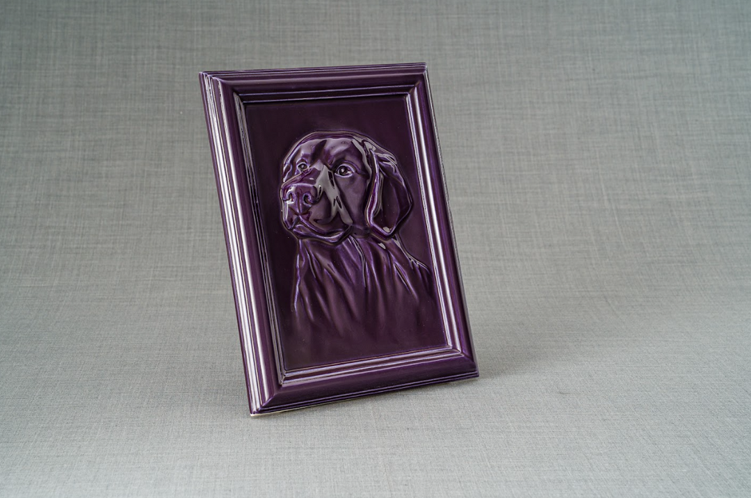 Purple glossy Labrador Frame Ceramic Urn with embossed Labrador portrait in a beveled frame on a gray fabric backdrop.
