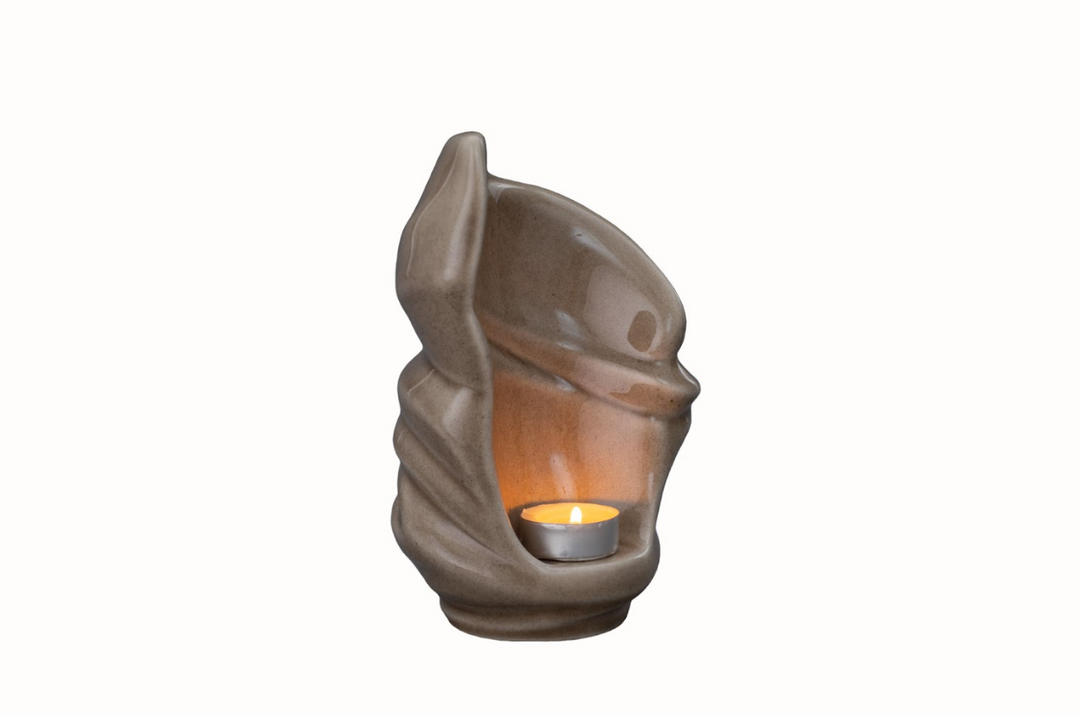Sculptural Light Ceramic Urn shown from the side with a lit tealight inside the hollow core.