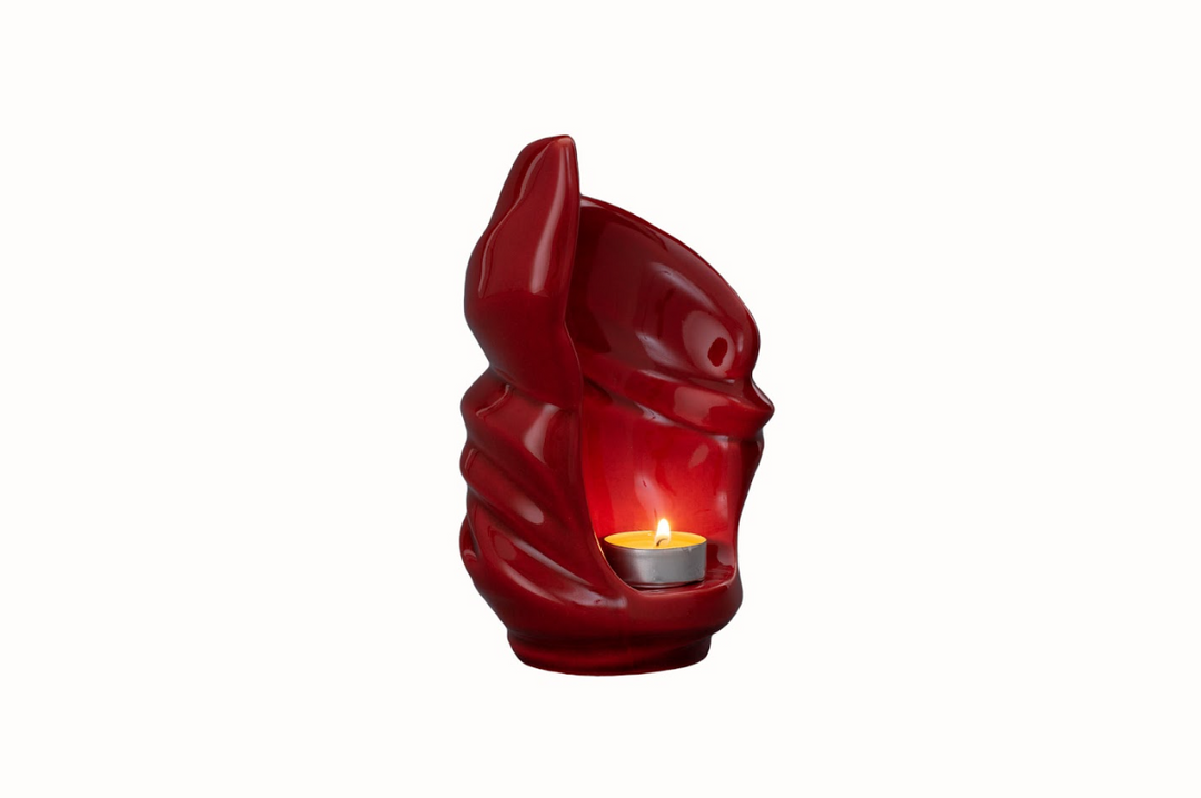Red ceramic Light Urn with a lit candle inside and flowing sculptural grooves