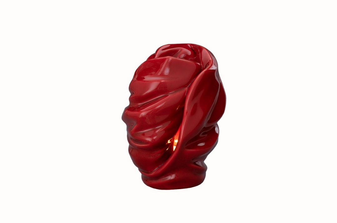 Red glazed Light Ceramic Urn candle holder with flame seen through the sculpted opening.
