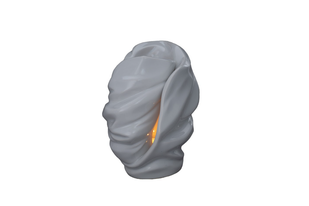 White Light Ceramic Urn with draped sculptural form and a lit candle glow inside