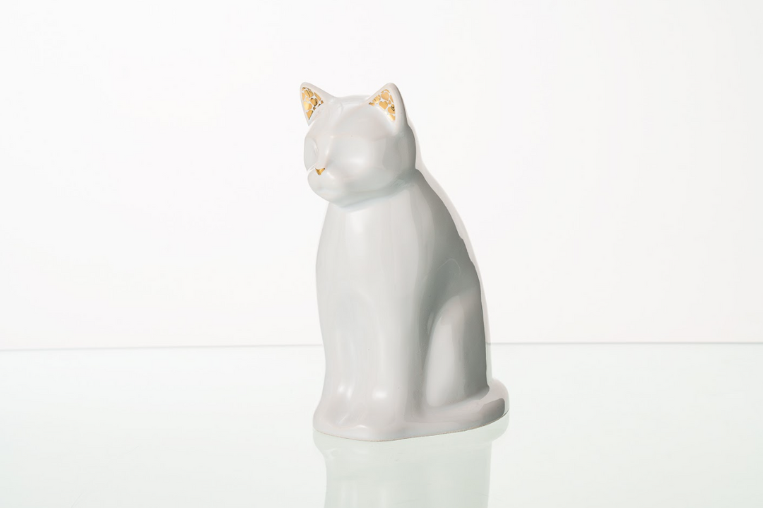 Glossy white Meow cat ceramic urn with smooth curves and gold accented ears on a reflective white surface.