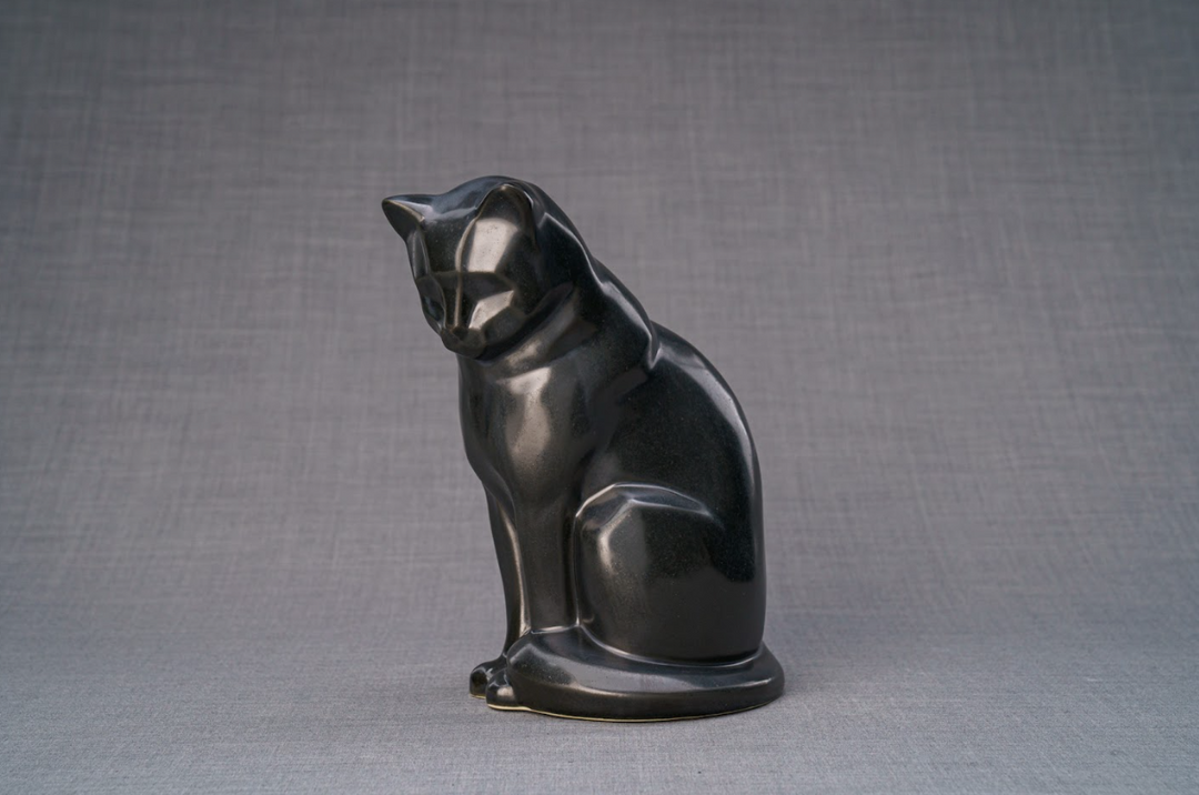 Side view of a matte black ceramic cat urn with tail wrapped at the base