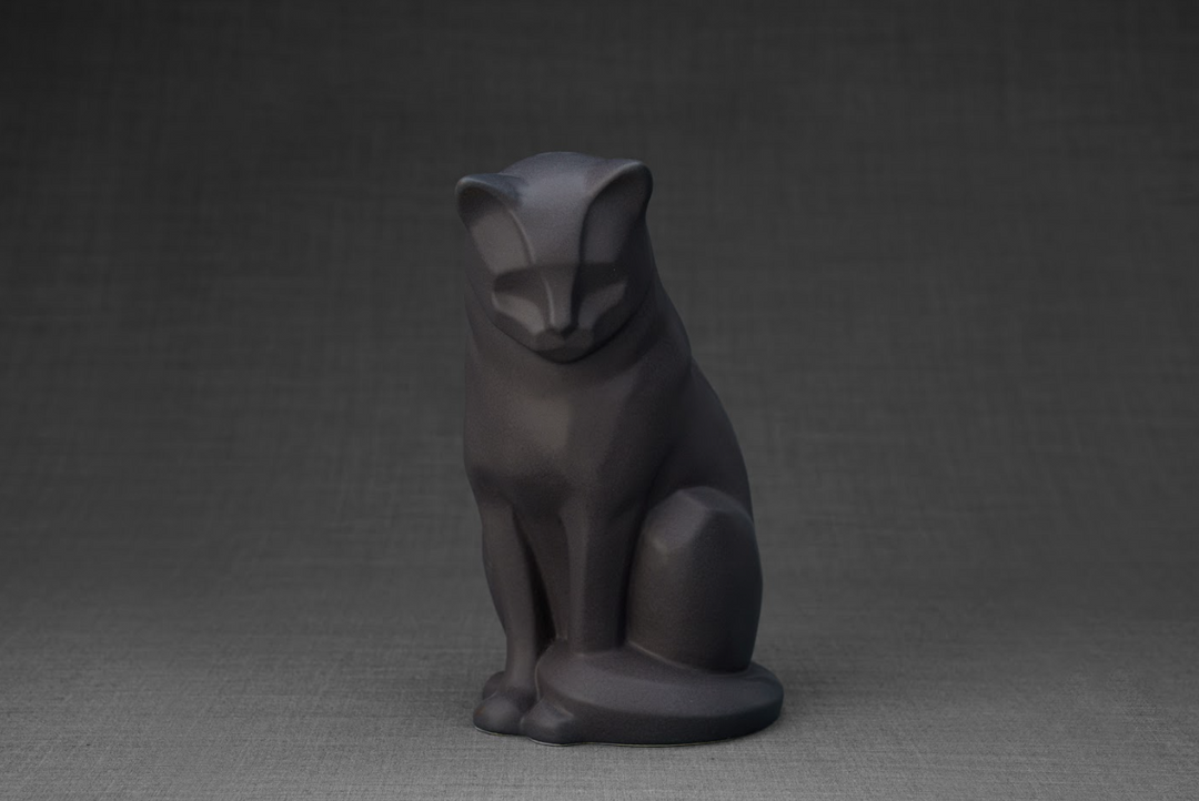 Three-quarter view of a dark matte ceramic cat urn in a seated pose