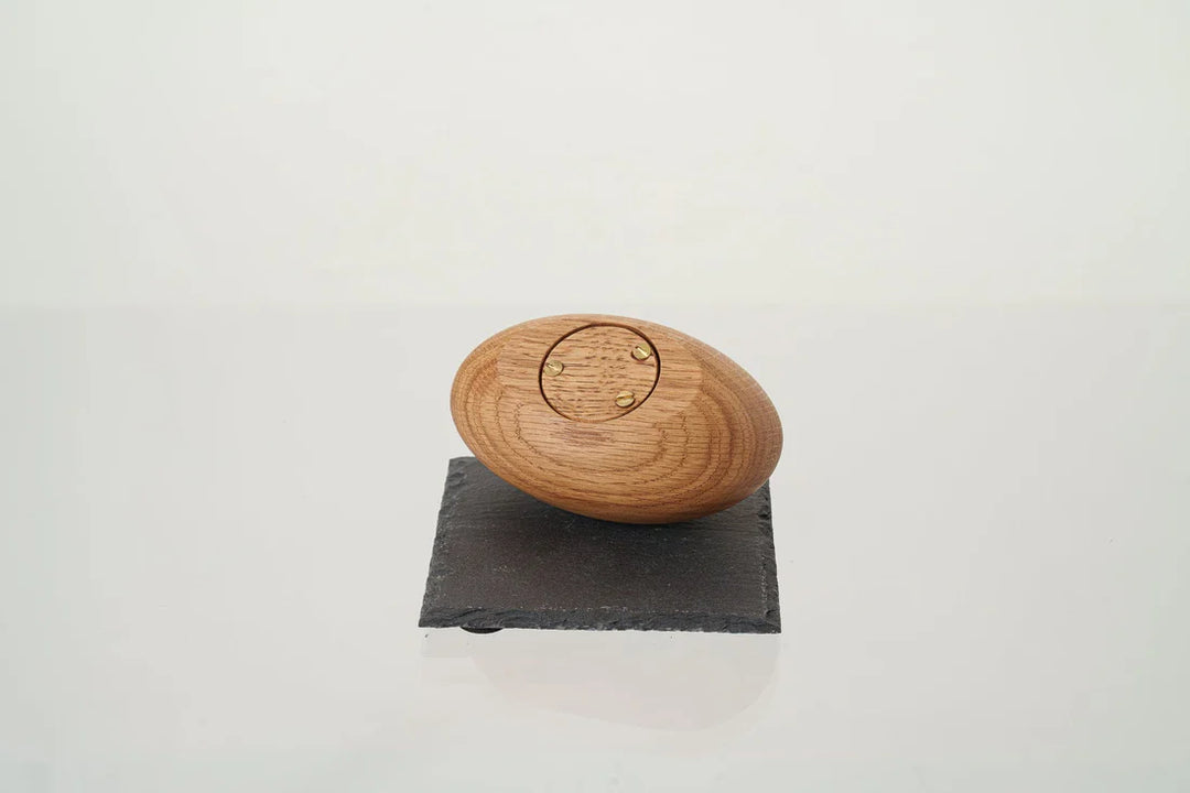 Bottom view of oval wooden keepsake urn showing circular lid with four gold screws