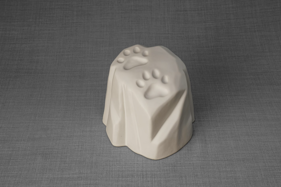 Cream stonelike ceramic urn with paw print impressions, a heartfelt memorial for a beloved pet.