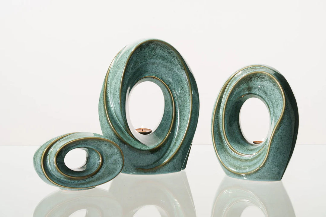 The Passage teal ceramic sculpture with circular openings and a built in candle holder for remembrance.