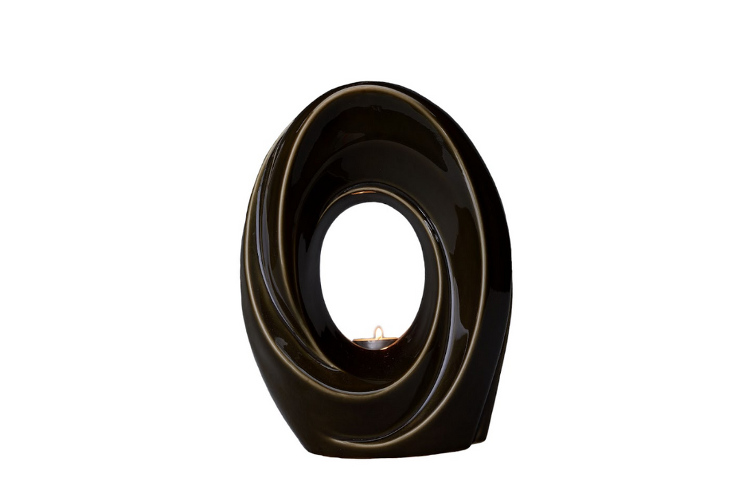 Dark glossy ceramic urn shaped in a swirling circular form with a candle inside.