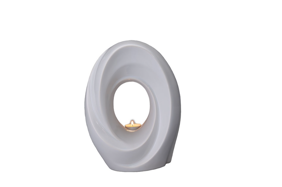 White ceramic urn with a circular loop design and a small candle visible in the inner opening.