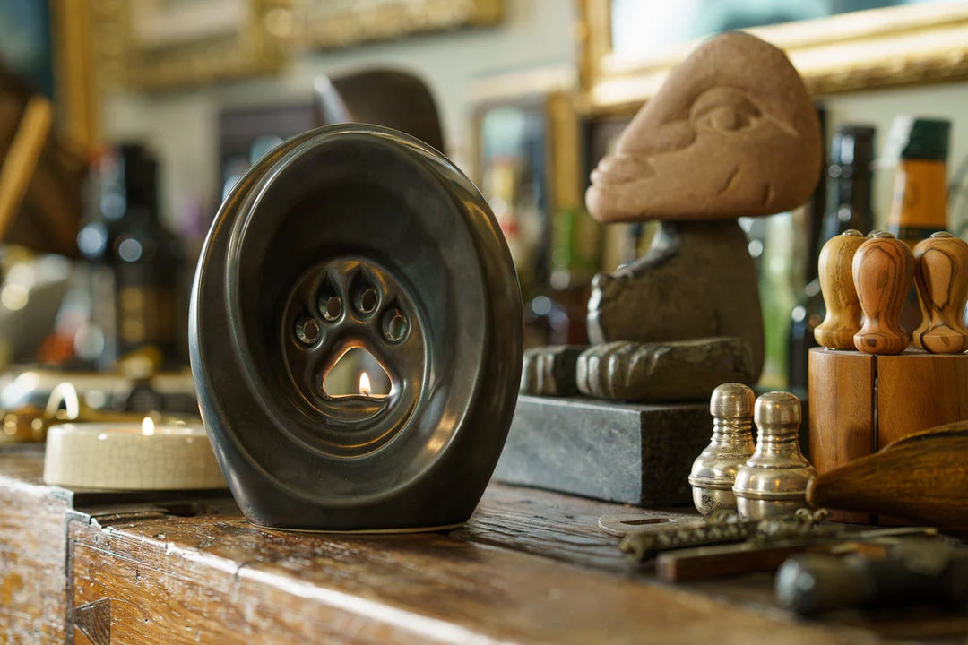 Black Paw Ceramic Urn with candle holder on a wooden workbench surrounded by art tools and supplies