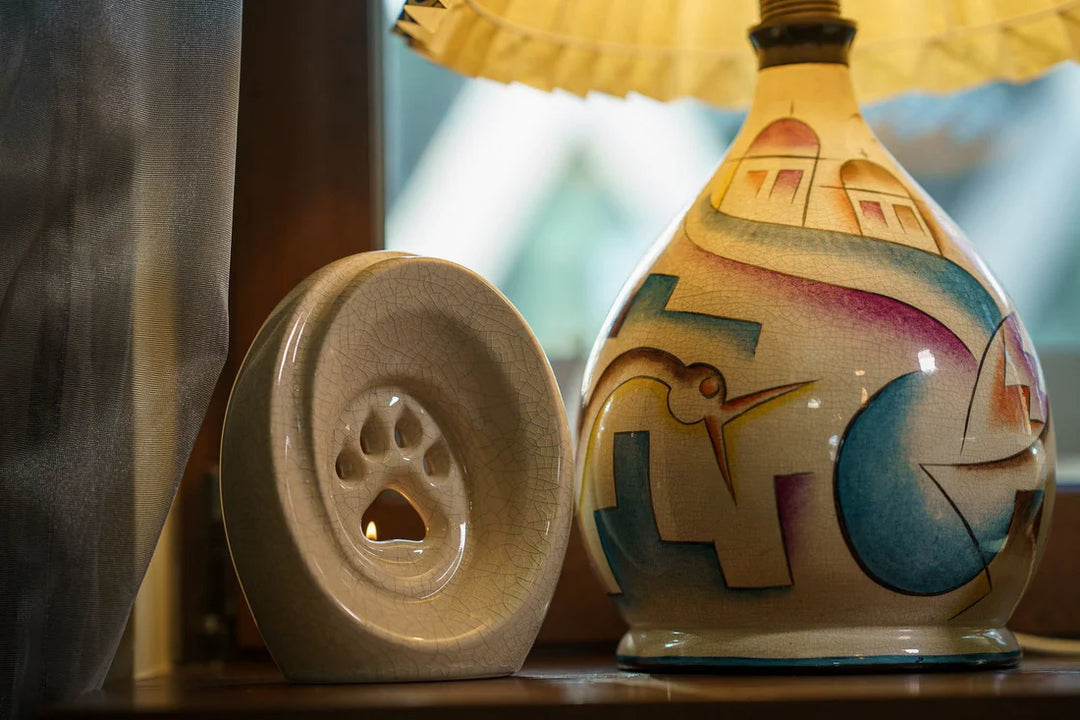 Colorful decorative paw ceramic urn for pet memorial with built in candle holder and a separate lid.