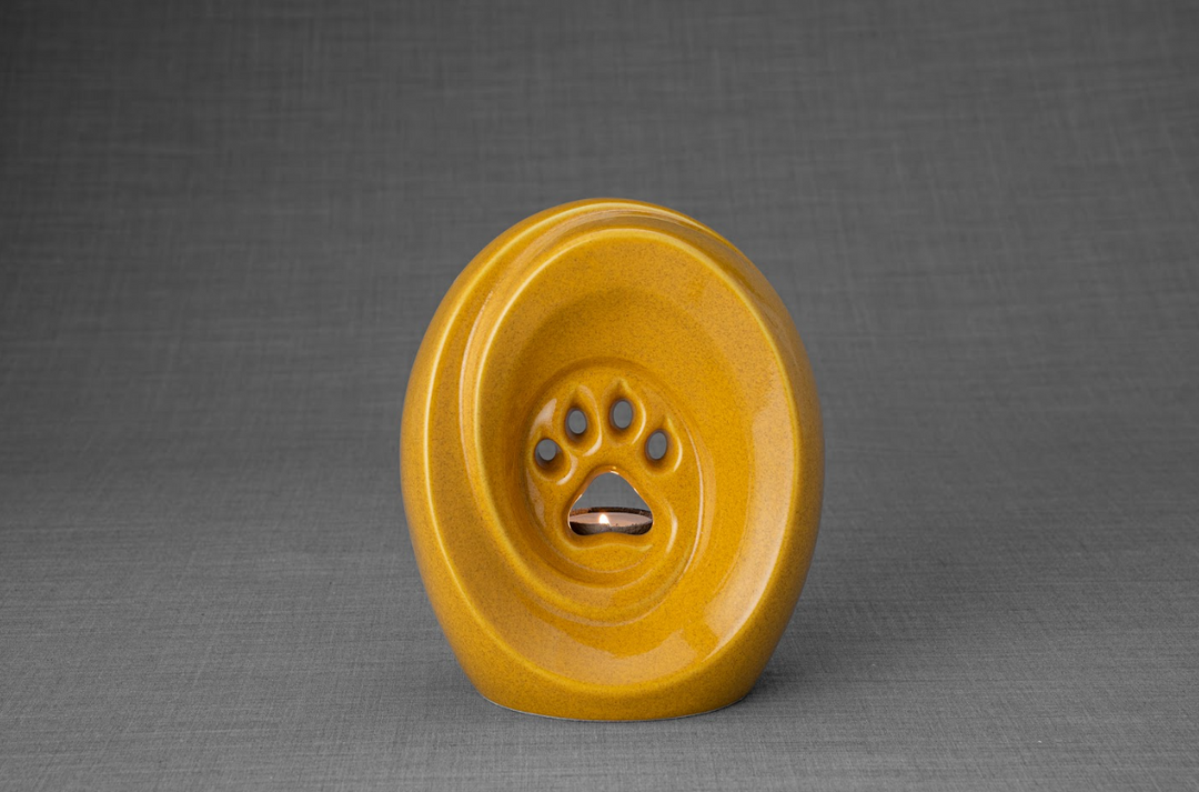 Bright yellow paw print ceramic urn featuring a built-in candle holder for pet remembrance.