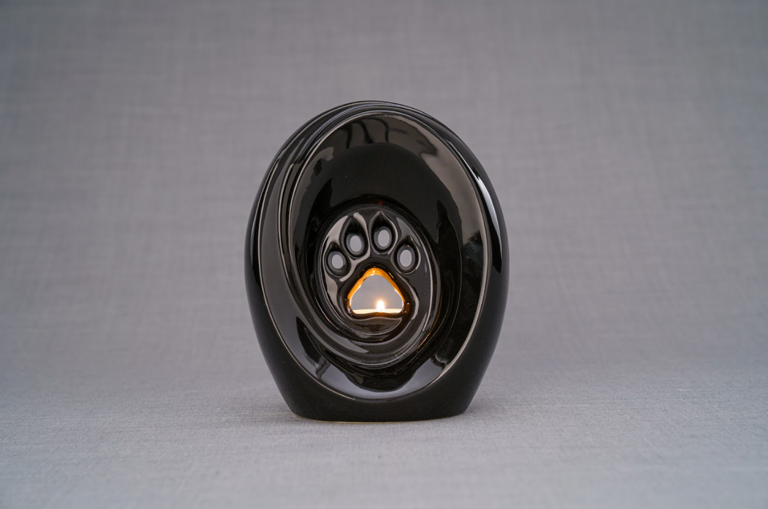 Glossy black Paw Ceramic Urn for pets with a built-in candle holder and paw print recess