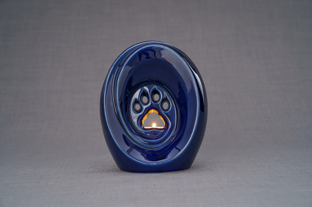 Blue glossy paw shaped ceramic urn with built in candle holder and a small flame