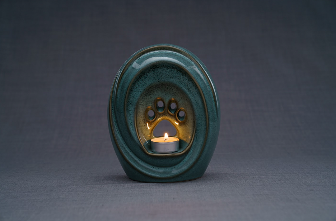 Front view of teal Paw Ceramic Urn featuring a candle holder and paw print cutouts.