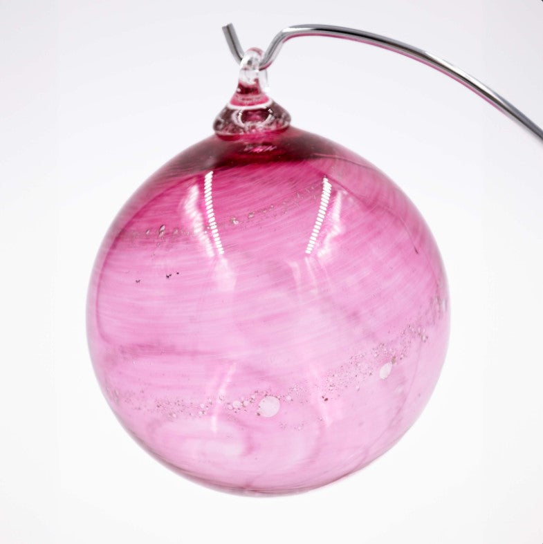 Pink hollow glass Christmas ornament infused with cremation ashes as a thin ribbon around the exterior.