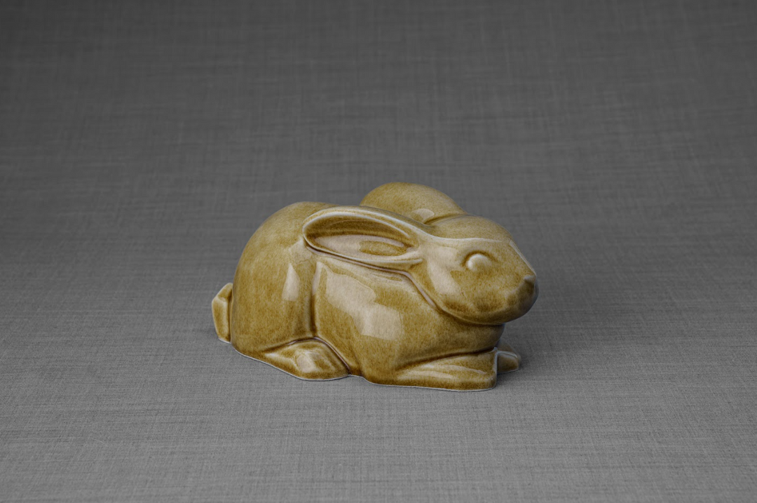 Light brown glazed ceramic rabbit urn in a relaxed reclining pose.