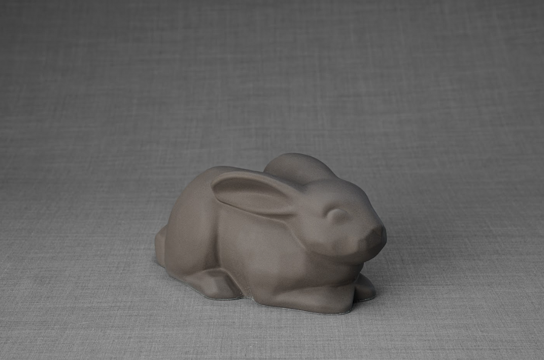 Matte gray rabbit shaped ceramic urn with smooth curves on a neutral backdrop.