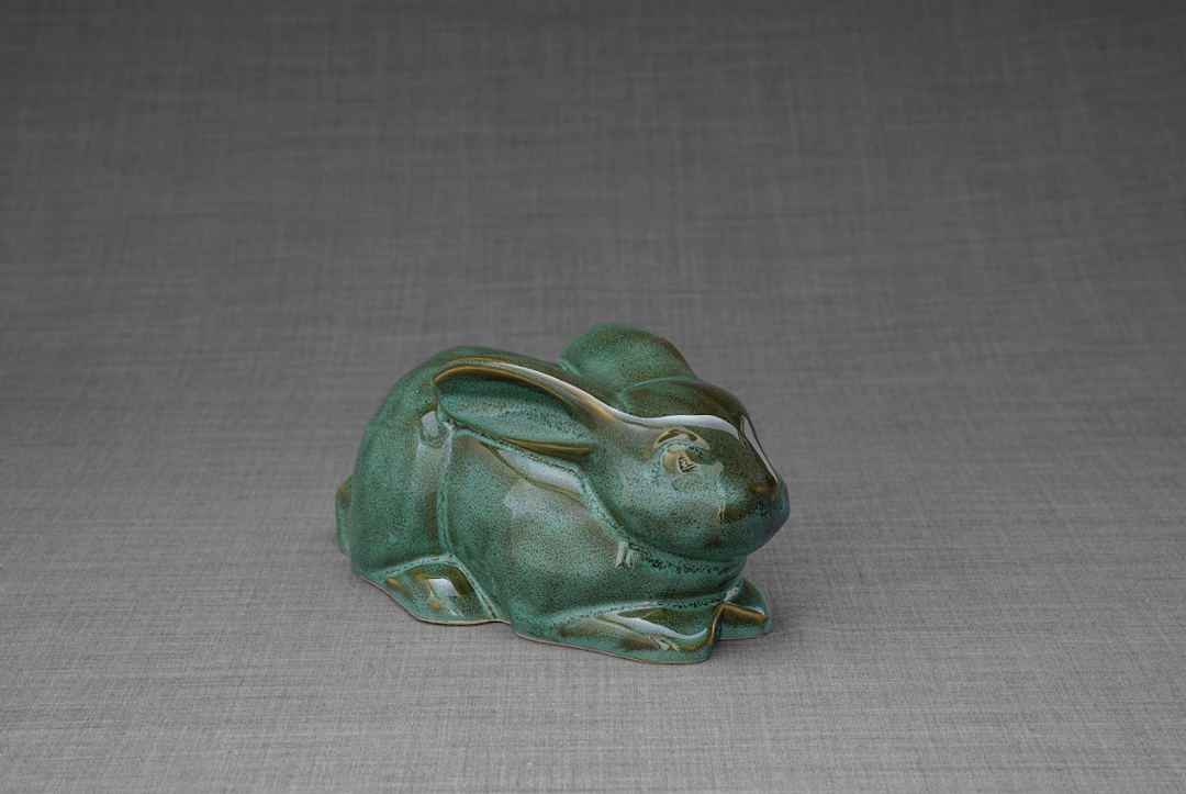 Green glazed ceramic rabbit urn in a resting pose, a memorial keepsake for a beloved bunny.