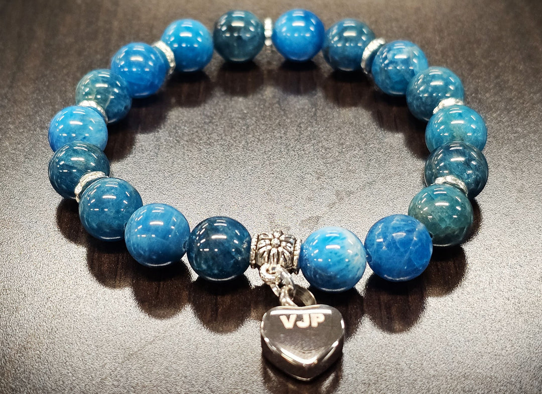Blue apatite bead bracelet with a keepsake urn heart charm for at home ashes on a dark surface