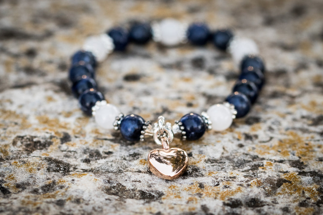Sodalite and Snow Quartz keepsake urn heart bracelet with a rose gold heart charm on a textured stone surface