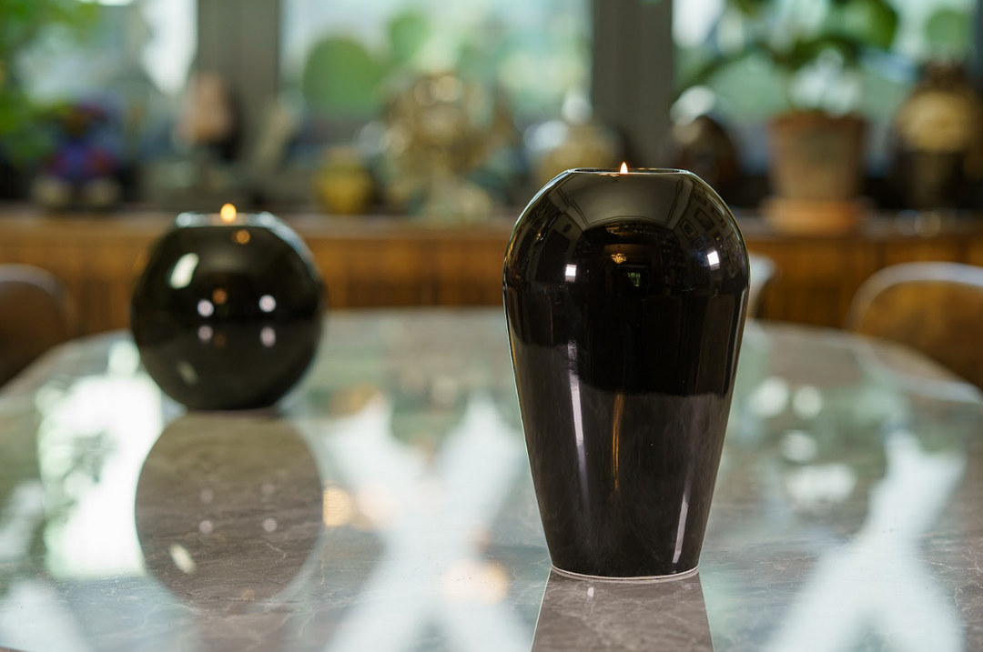 Front view of a glossy black Serenity urn on a marble surface with a softly blurred background.