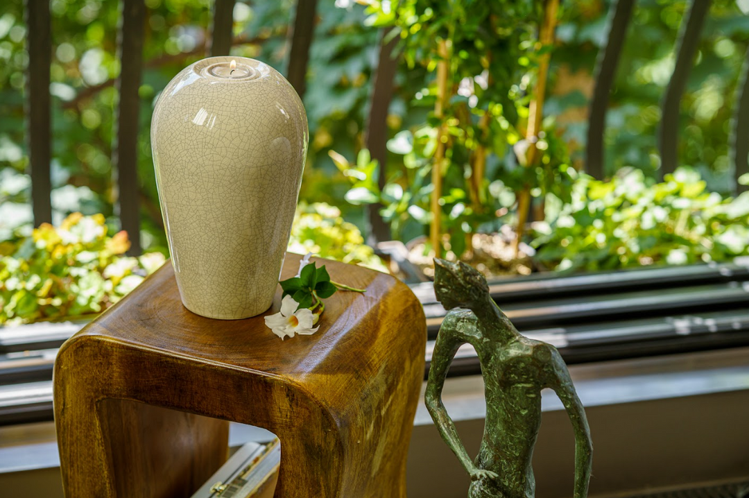 Serenity ceramic urn with crackle glaze and built in tea light holder atop a wooden pedestal.