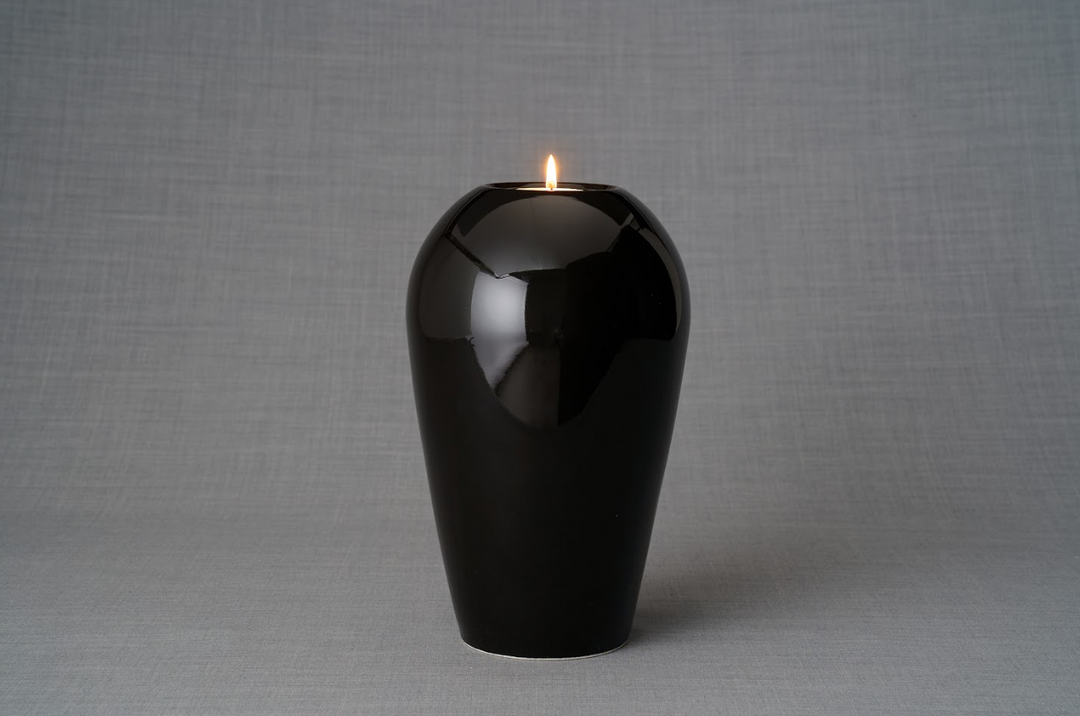 Glossy black Serenity urn with a lit tea light resting on its top.
