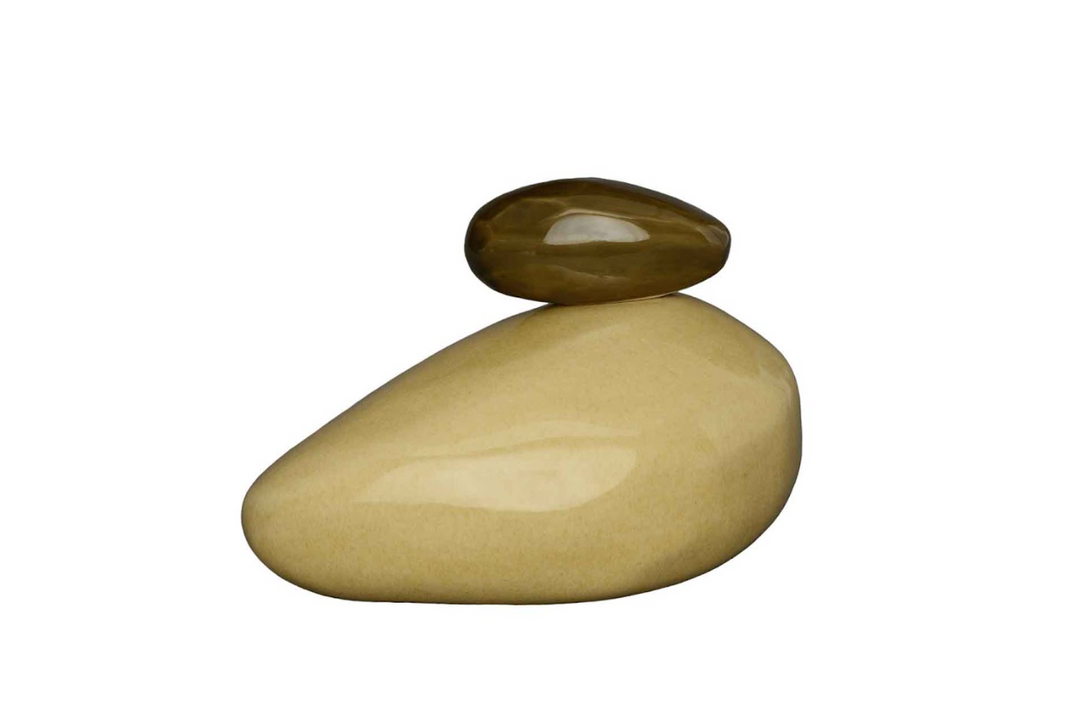 Two smooth stones stacked, a tan base with a small brown top stone on a white background