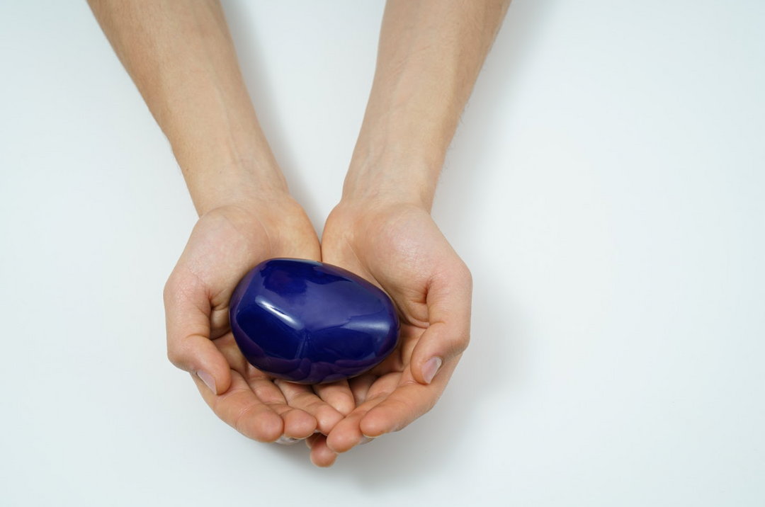 Hands cupping a glossy deep blue stone color sample for the Stone Ceramic Urn