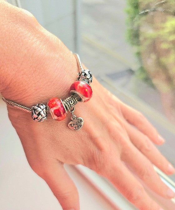 Beaded bracelet featuring red strawberry cheesecake beads infused with cremation ashes worn on a wrist.