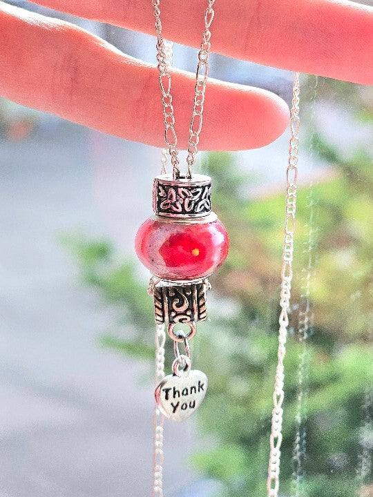 Cremation ashes bead pendant on a delicate silver chain with ornate caps and a Thank You charm.