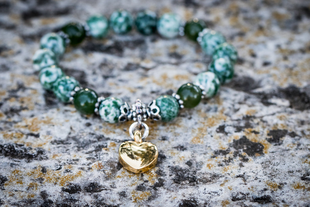 Tree Agate and Malaysian Jade keepsake urn heart bracelet with a gold heart charm on a textured stone surface
