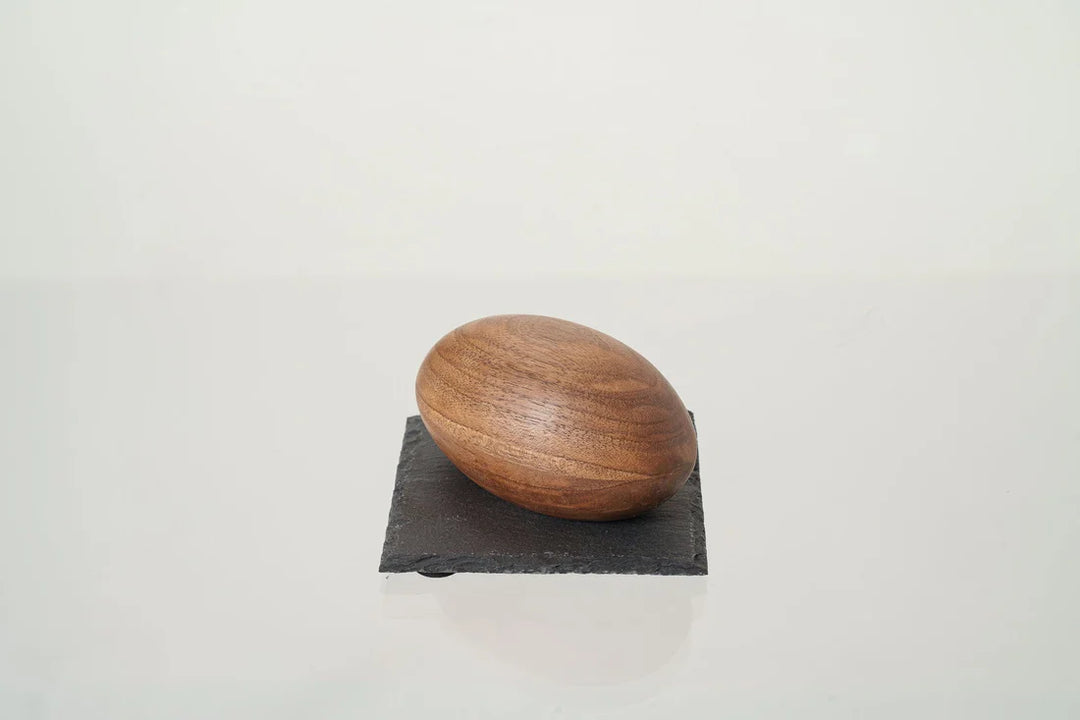 Single wooden keepsake urn resting on a dark slate square against a light background.
