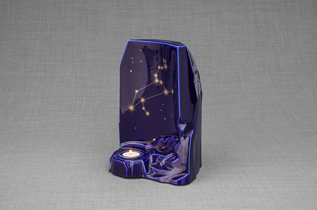 Side view of the deep blue zodiac ceramic urn showing a star constellation design and candle base.