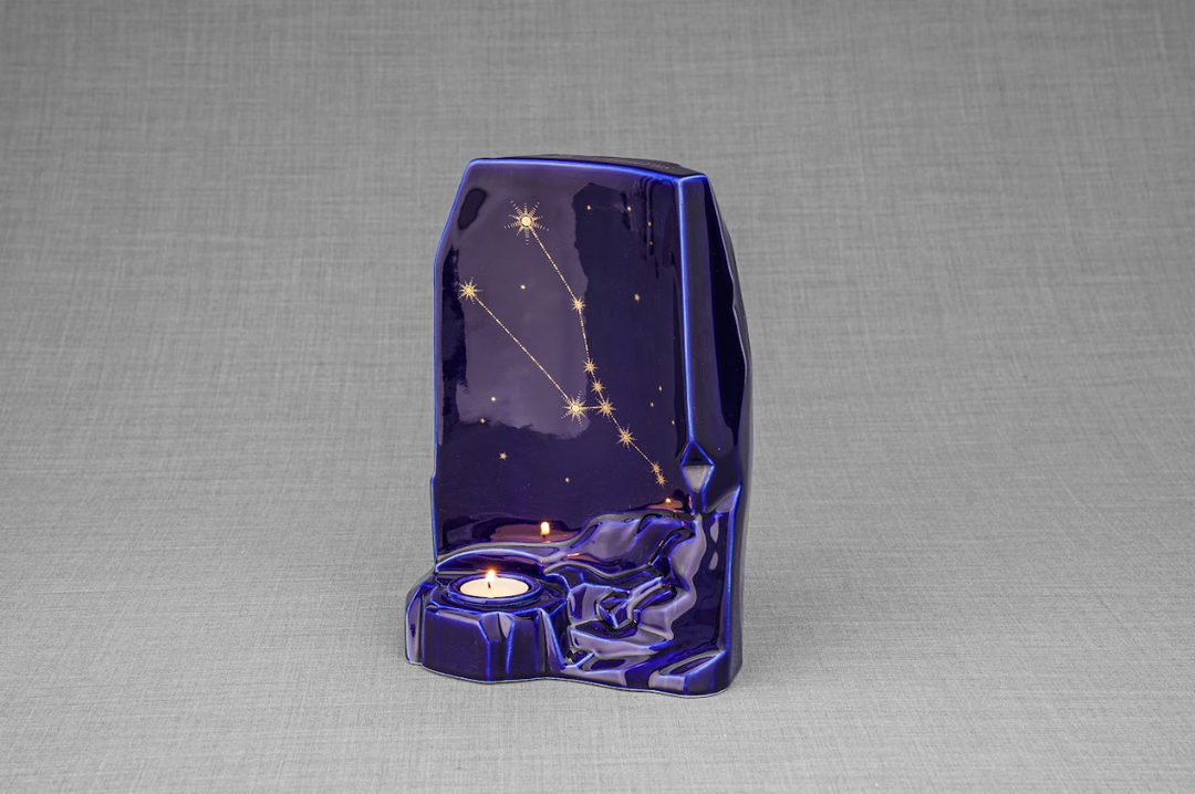 Angular view of the deep blue Zodiac Ceramic Urn showing the gold constellation map and candle holder at the base.
