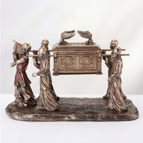 Four robed figures carry an ornate Ark of the Covenant keepsake urn on a long bronze base against a light background