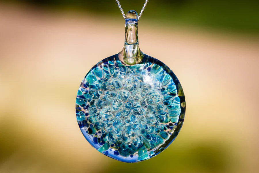 Blue moon pendant infused with cremation ashes featuring a glass disc with blue bubbles on a silver chain