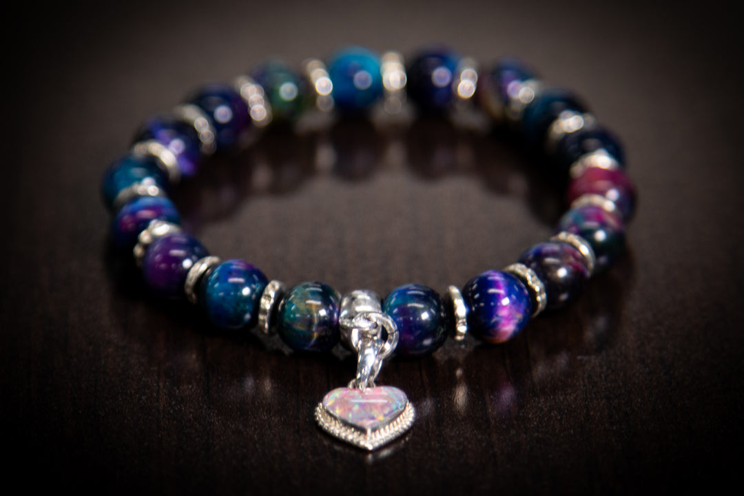 Rainbow Tiger Eye cremation bracelet with a sterling silver charm filled with crushed opal and ash in pink and blue tones.