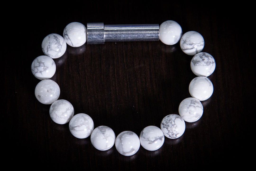 White and gray marbled howlite bracelet with a silver tube clasp on a dark background