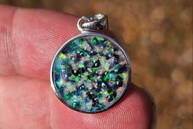 circle pendant with cremation ash held in fingers