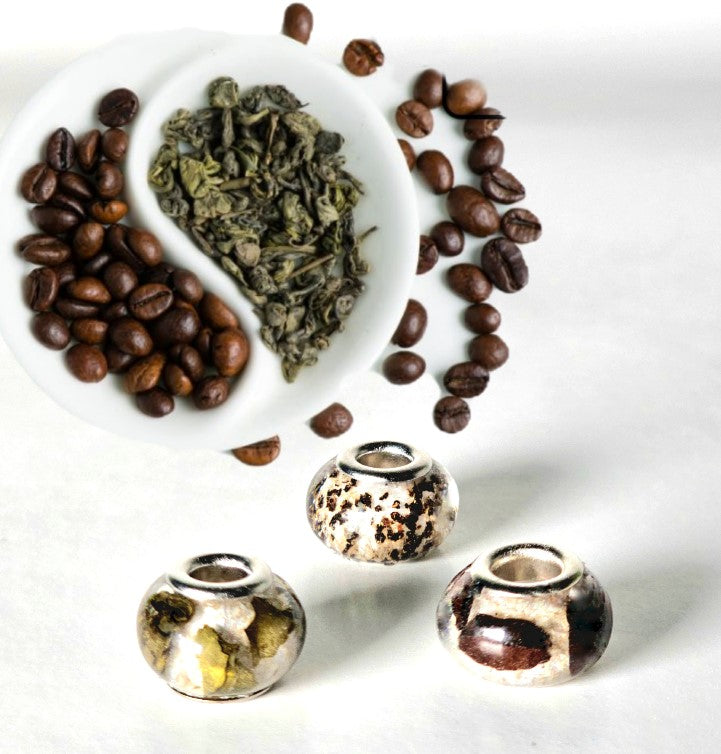 Three round cremation ash beads infused with coffee or tea, shown with coffee beans beside a white cup.