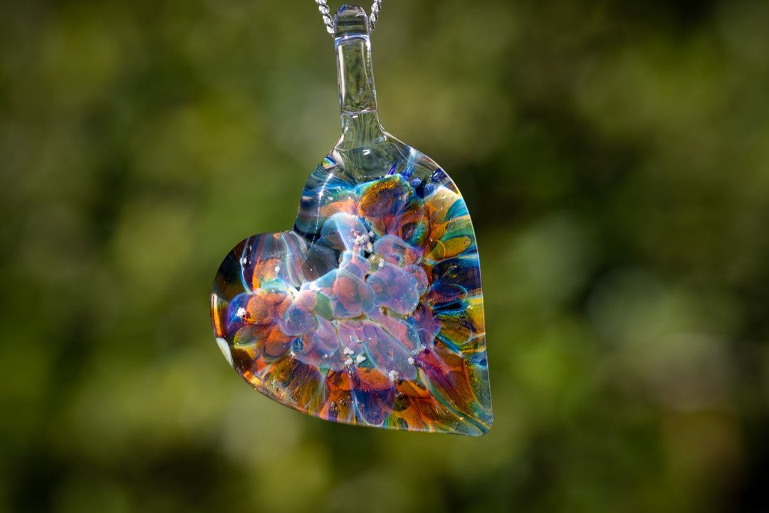 Rainbow glass heart pendant infused with cremation ashes, hanging from a silver chain.