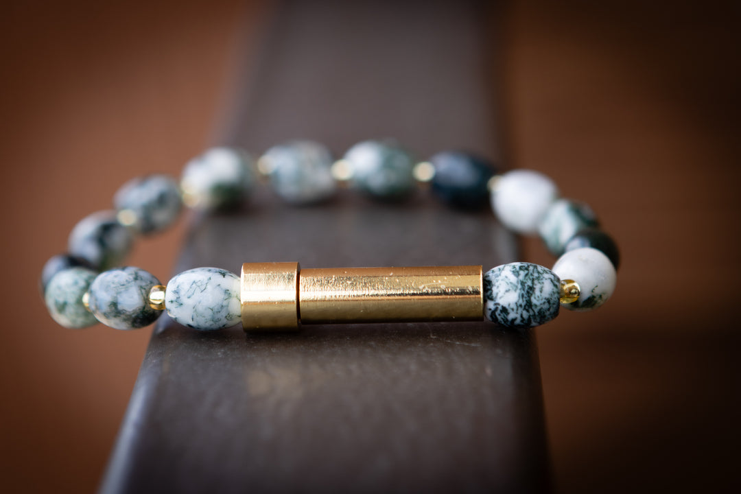 Creamtion Bracelet with blue beads and gold clasp on a dark surface