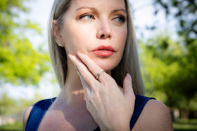 cremation ring being worn by Woman with hand on chin in a park setting