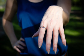 cremation ring being worn by Woman with hand on chin in a park setting
