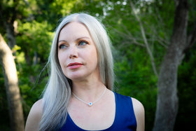 Woman wearing a cremation necklace from ashes of pets and people with long silver hair standing in a forest