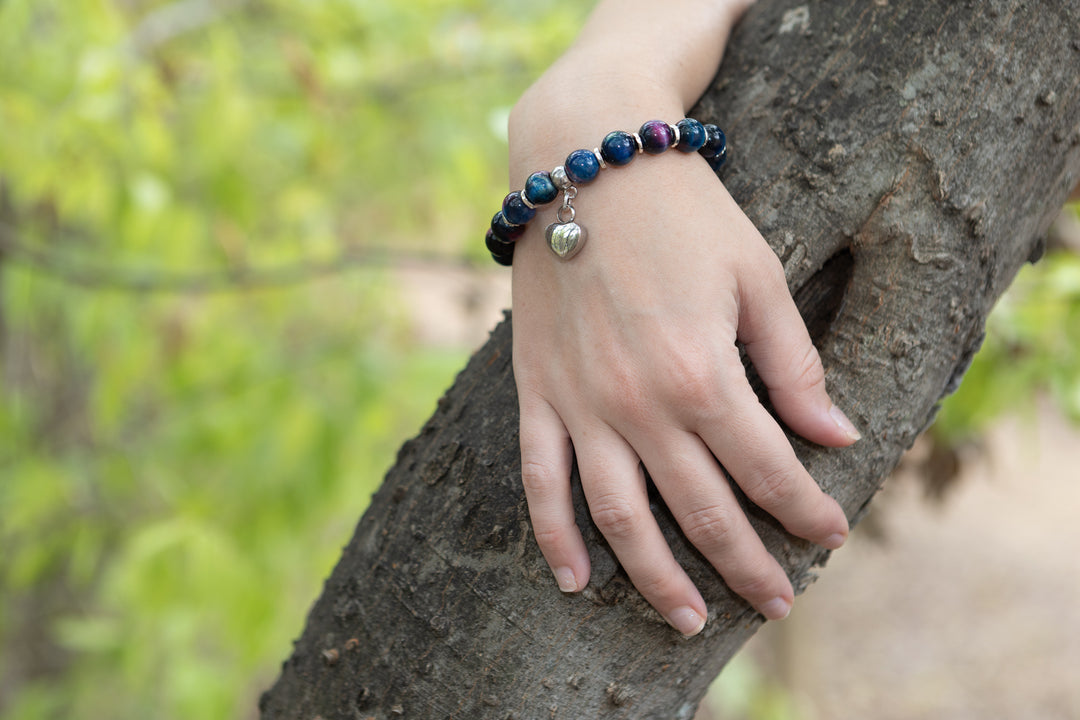 Rainbow tiger eye bead bracelet with a silver heart keepsake charm on the wrist