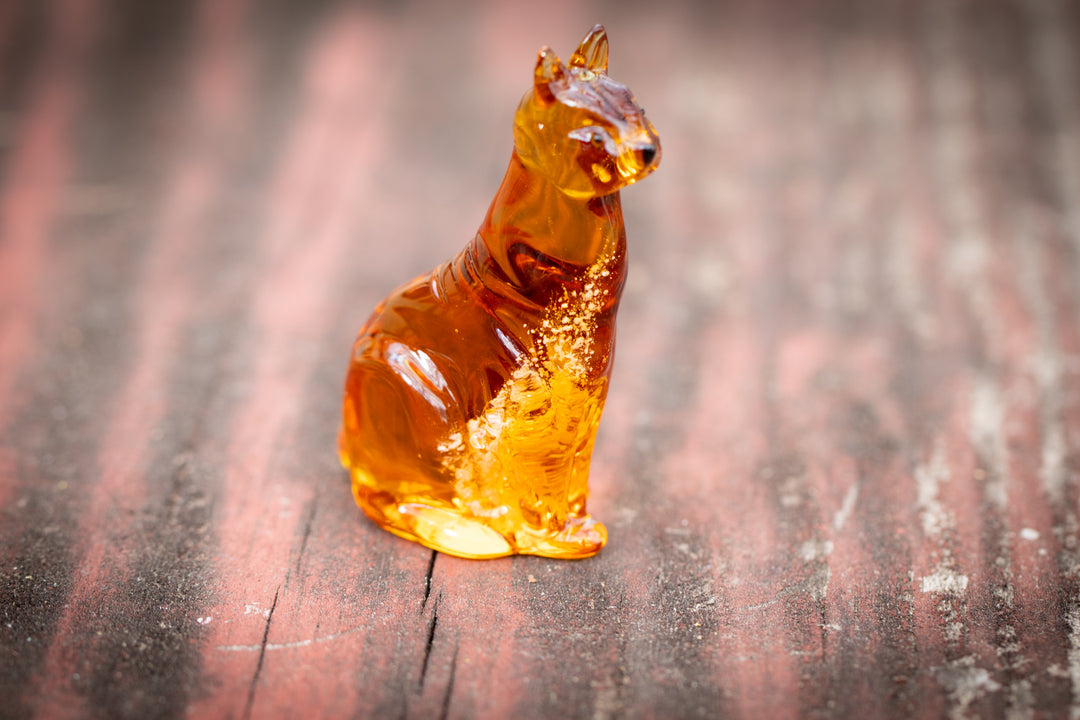 Amber glass cat figurine in a seated pose with cremation ashes visible inside